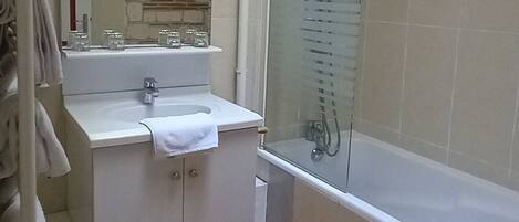 A bathroom with a skylight, a bathtub, a shower, and a vanity with a mirror.