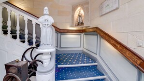 A staircase with a white balustrade, a statue, and a blue carpet with a pattern. - Brit Hotel Les Comtes de Champagne Centre Historique (Troyes)