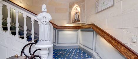 Een trap met een witte balustrade, een standbeeld en een blauw tapijt met een patroon.