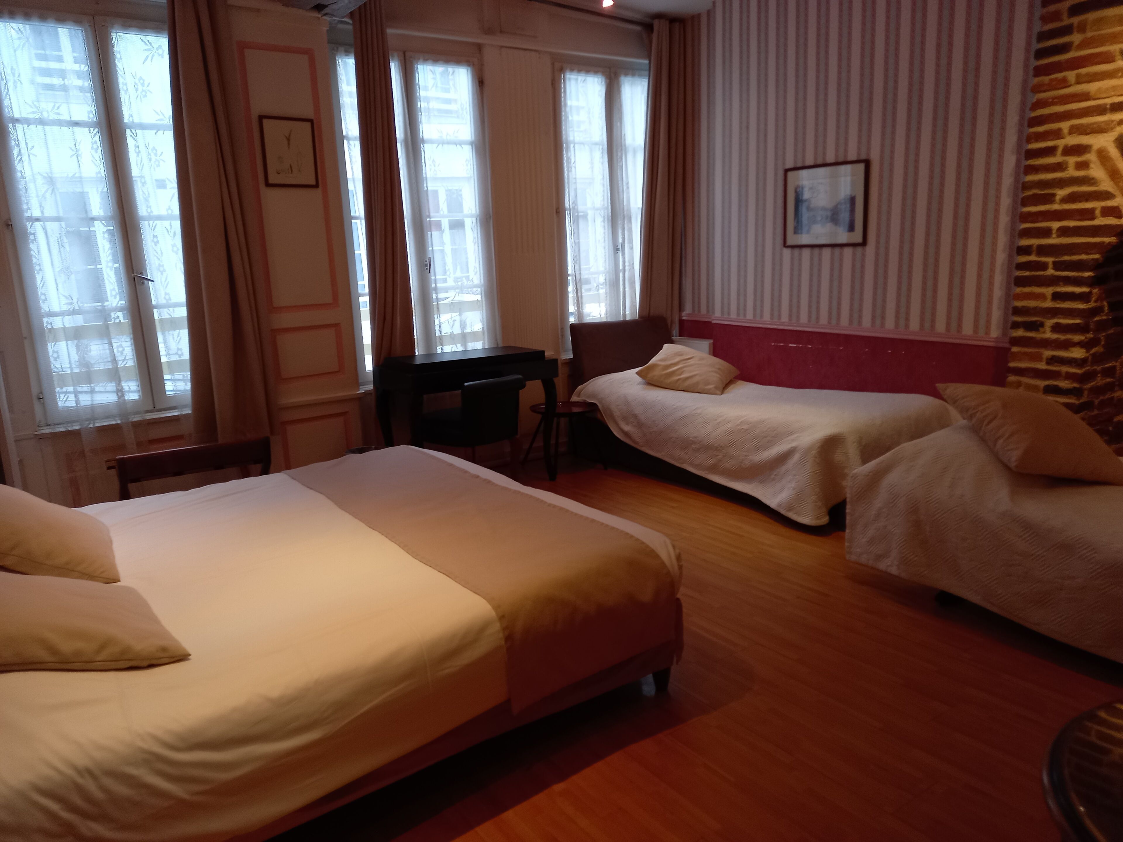 A hotel room with two beds, a desk, and a chair.