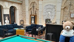 A billiards table with balls, a plush sofa, and a bear mascot in a hotel lobby with stone walls and a glass ceiling. - Brit Hotel Les Comtes de Champagne Centre Historique (Troyes)