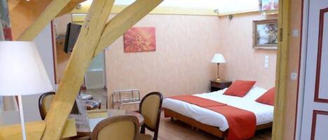 A bedroom with a bed, a desk, chairs, a lamp, and a painting on the wall.