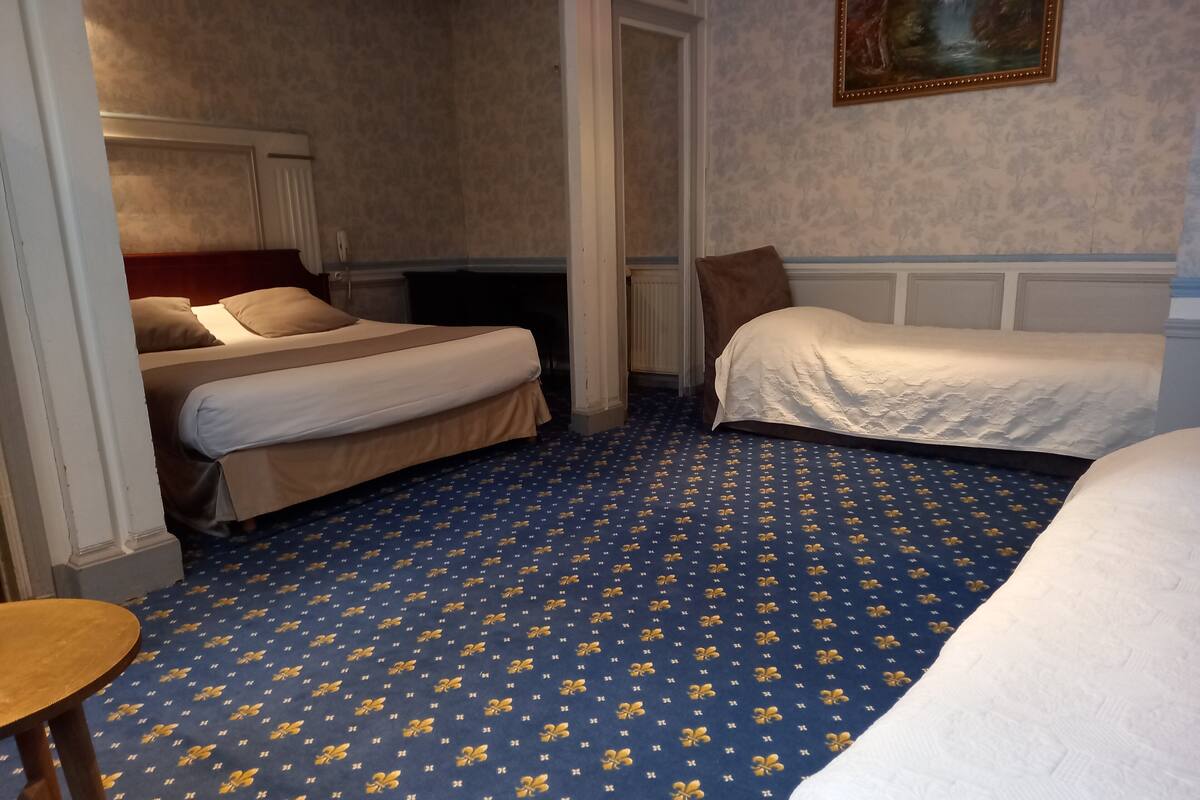 Ein Hotelzimmer mit zwei Betten, einem Holzstuhl und einem gemusterten Teppich.