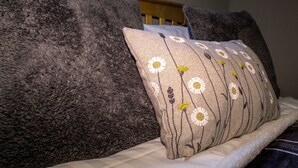 A bed with a fluffy grey blanket and a pillow with a floral pattern.