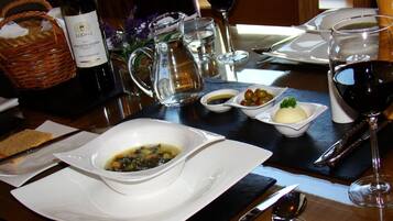 A dining table set with a bottle of wine, a pitcher, glasses, and plates with food.