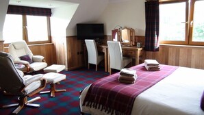A hotel room with a bed, a desk, a television, a chair, and a sofa. - Binnilidh Mhor B&B (Inverness)