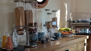 A breakfast bar with various food dispensers, a clock, and a fruit bowl. - Binnilidh Mhor B&B (Inverness)
