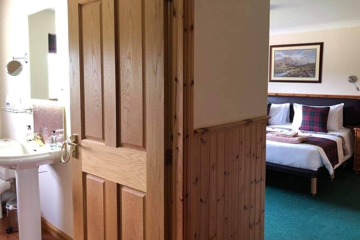 A wooden door leading to a bathroom with a sink and mirror.