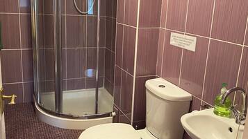 Une salle de bain avec une douche, des toilettes, un lavabo et un mot écrit sur le mur.