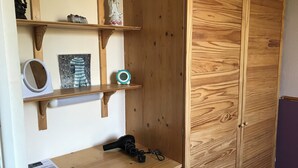 A wooden wardrobe with a mirror and shelves holding decorative items. - Camelot Retreat (Glastonbury)