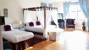 A spacious bedroom with two beds, a sitting area, and a large window with curtains. - Cuil an Daraich Guest House (Pitlochry)