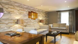 A modern living room with a stone wall, two sofas, a coffee table, and a dining table. - Five Star Stays (Scarborough)