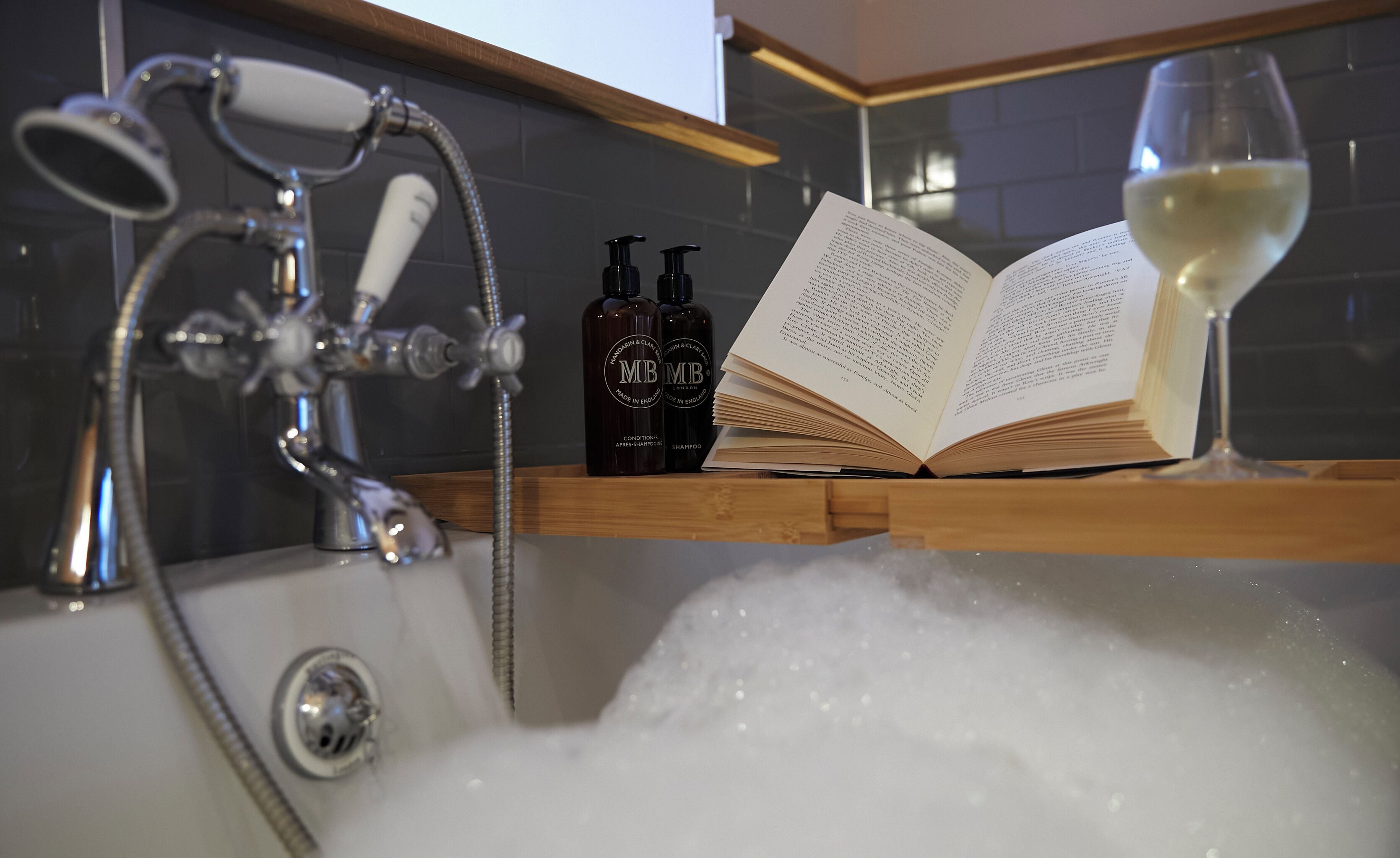 Una bañera con agua corriente, un libro y dos botellas de champú.