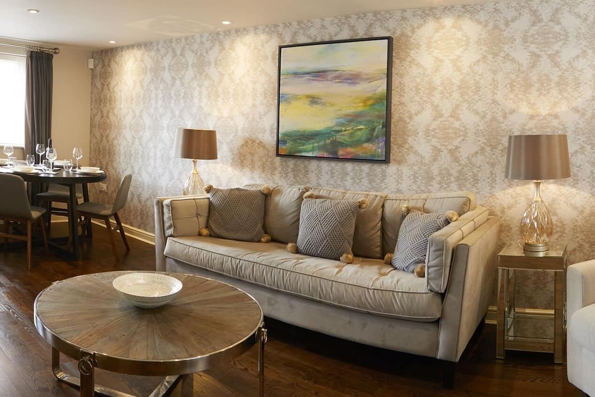 Een woonkamer met een bank, een rond bijzettafeltje en een eethoek met stoelen en een tafel.