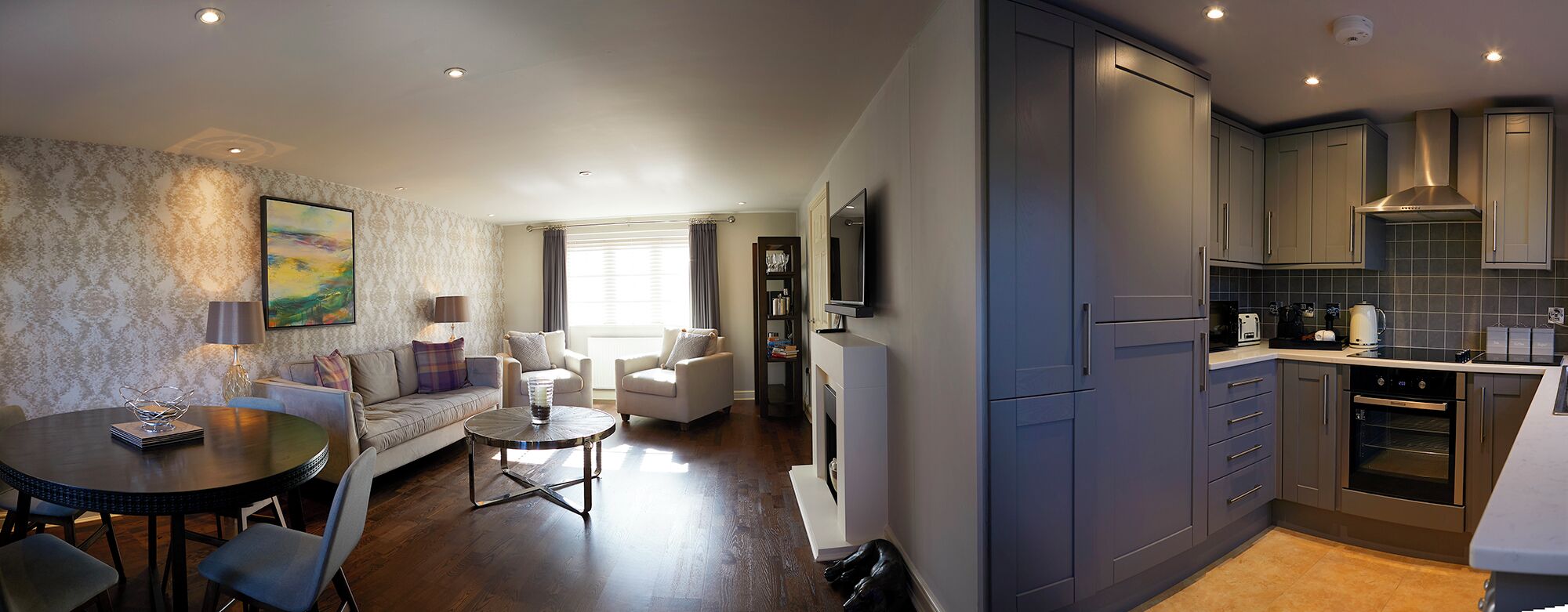 A modern apartment with a living room, dining area, and kitchen.