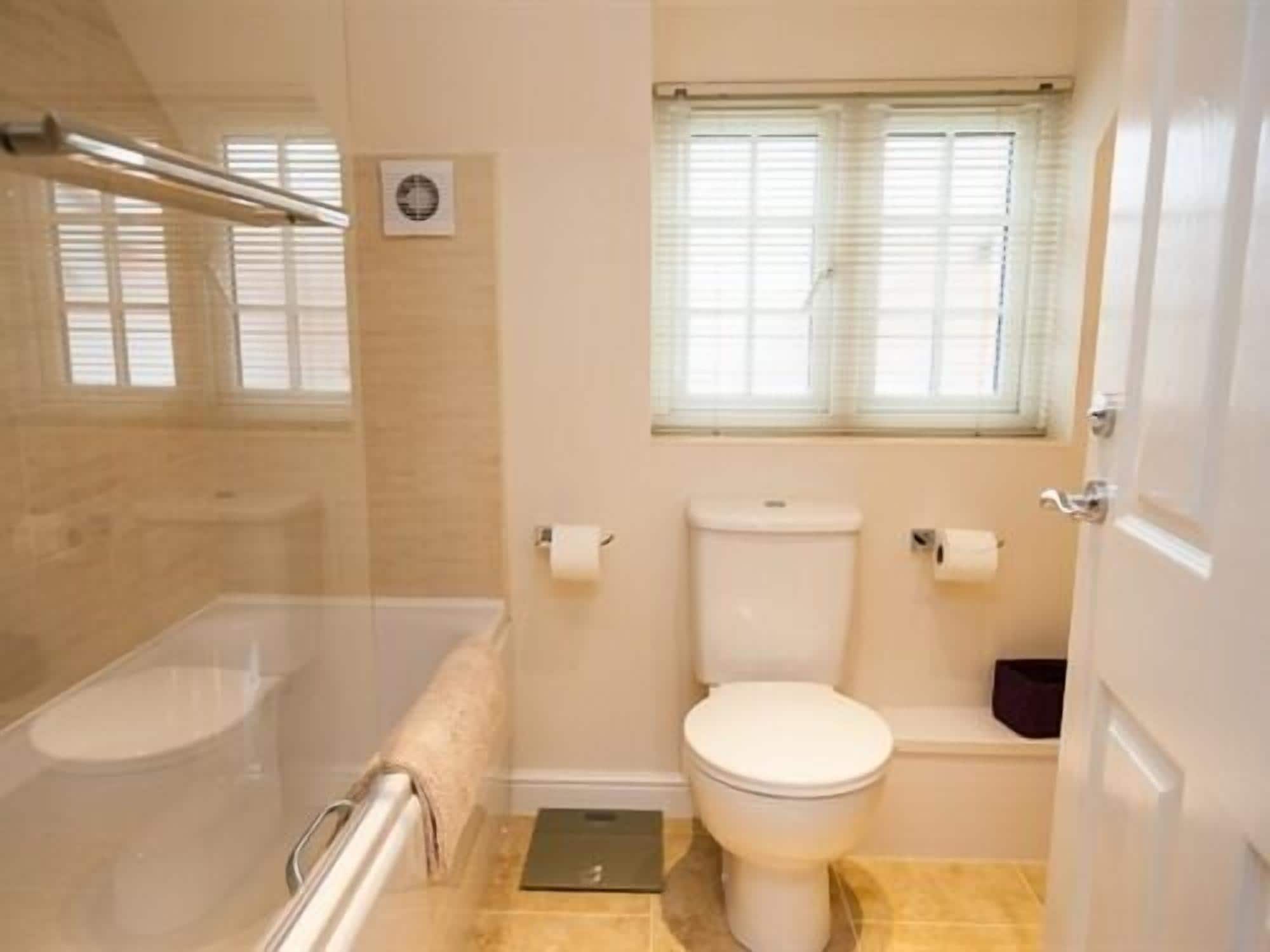 A bathroom with a toilet, a shower, and a window.