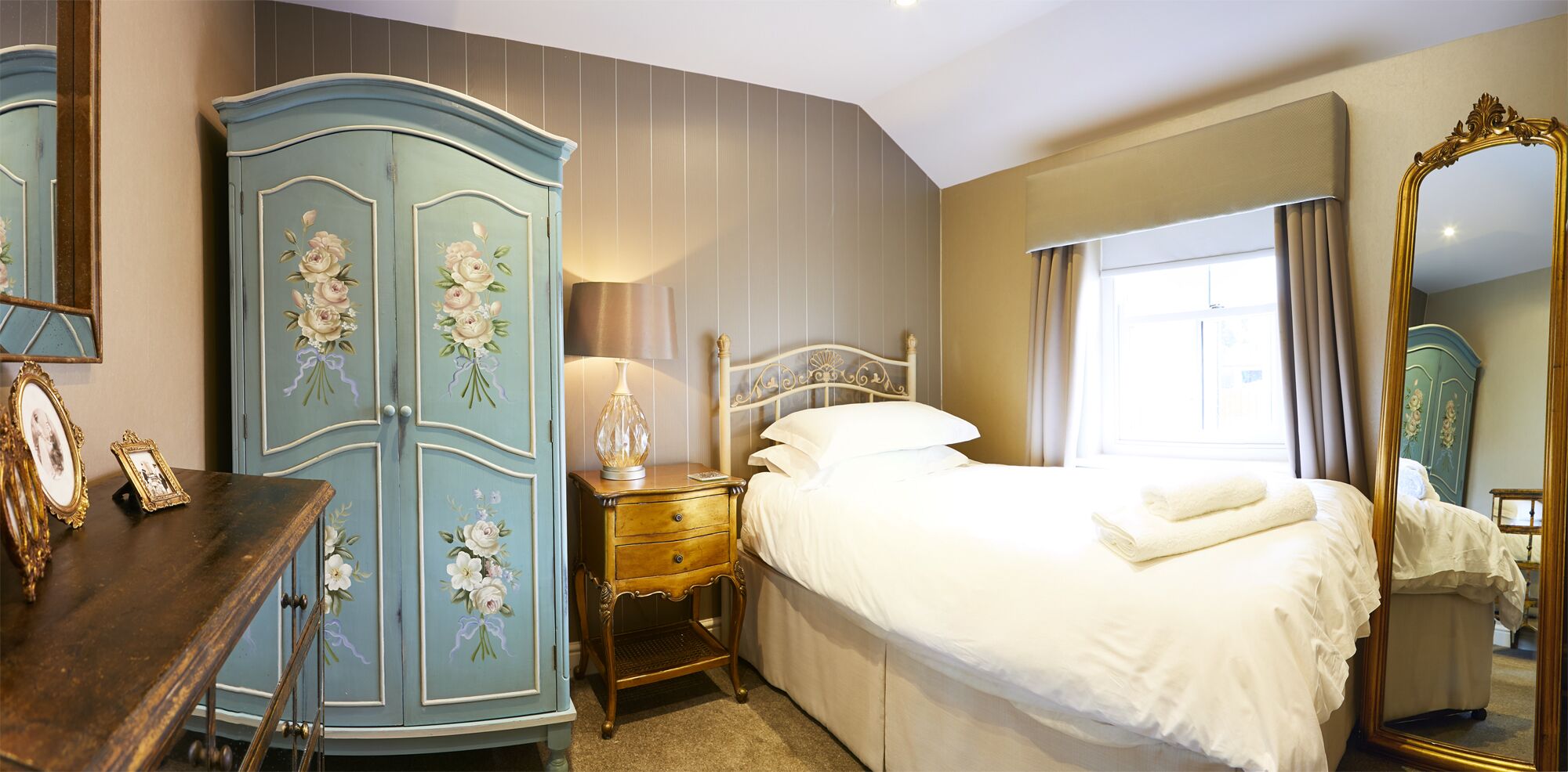 A bedroom with a bed, a dresser, a nightstand, and a mirror.