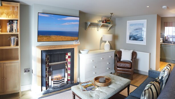 A living room with a fireplace, a television, a sofa, and a bookshelf. - Five Star Stays (Scarborough)