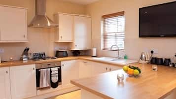 Una cocina moderna con armarios blancos, una campana extractora de acero inoxidable, un horno empotrado, un fregadero y una encimera de madera.
