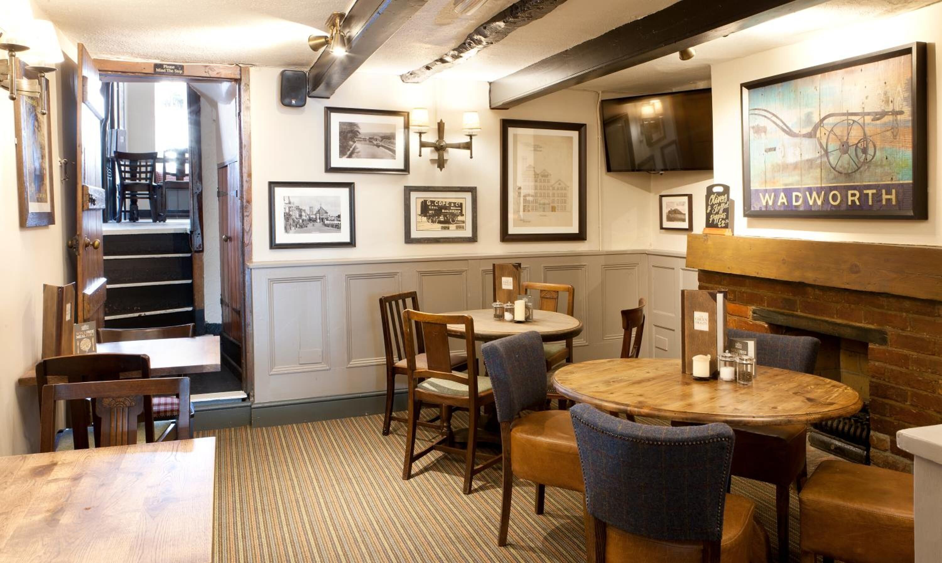 L’intérieur chaleureux du restaurant est agrémenté de tables et de chaises en bois, de tableaux encadrés aux murs et d’un téléviseur fixé au-dessus d’une cheminée.