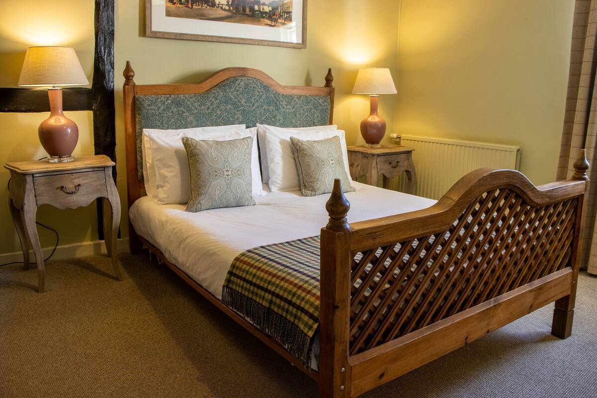 A neatly made bed with a wooden headboard, two bedside tables with lamps, and a framed picture on the wall.