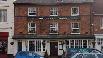 A traditional pub named "The Green Dragon" with a brick facade, white windows, and a green awning.