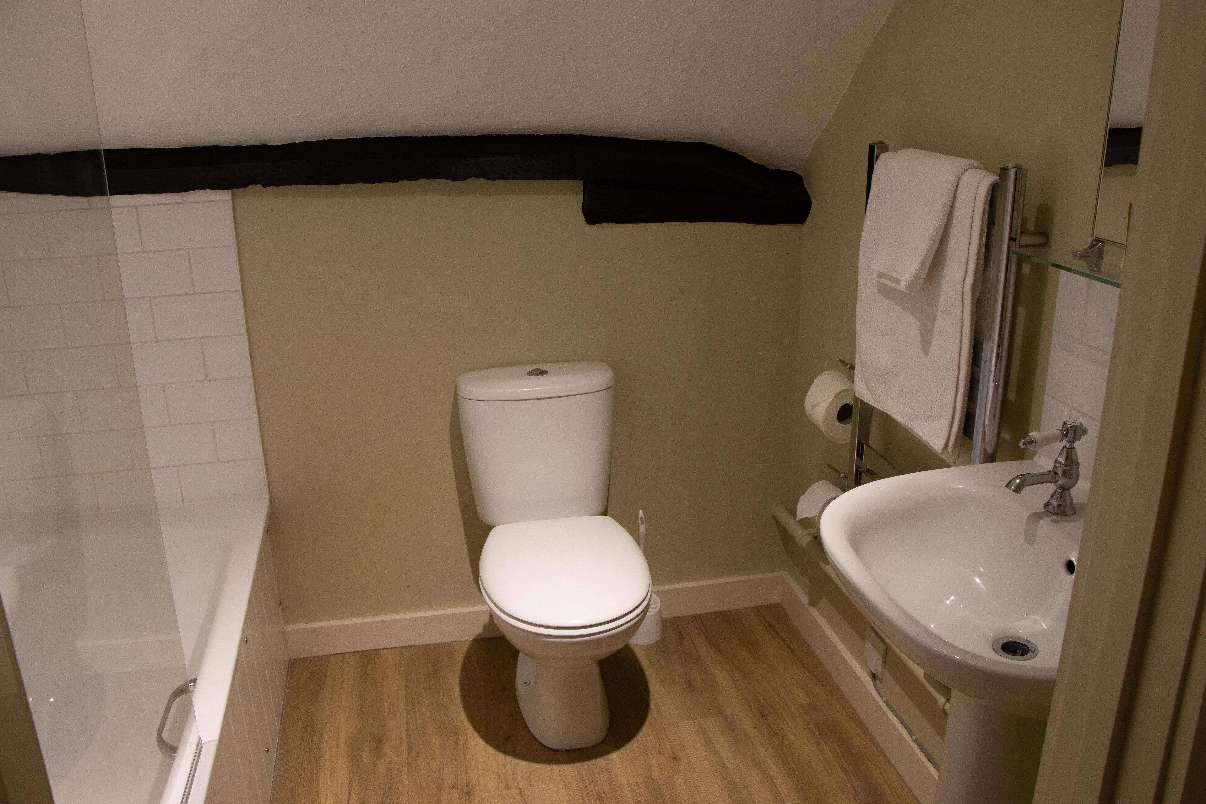 A small bathroom with a toilet, sink, and shower.
