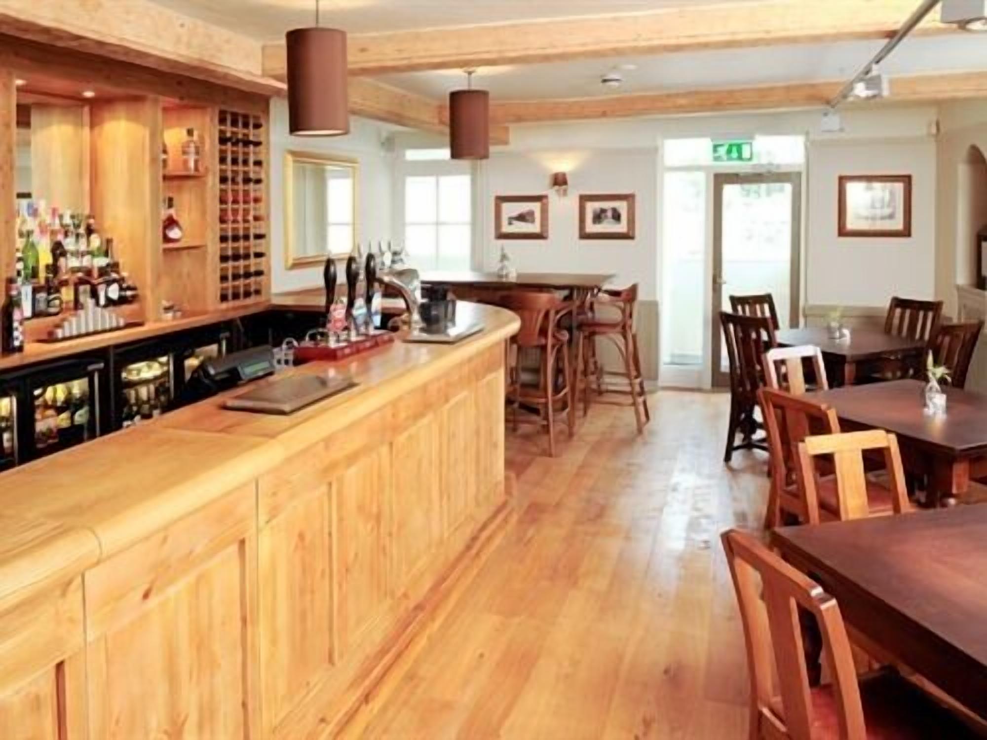 A bar area with wooden cabinets, a counter, and a seating area with tables and chairs.