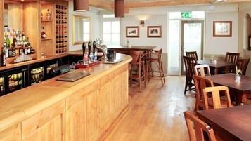 A bar area with wooden cabinets, a counter, and a seating area with tables and chairs.
