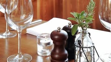 A wooden table with a glass candle, a salt and pepper shaker, and a glass vase with a plant.
