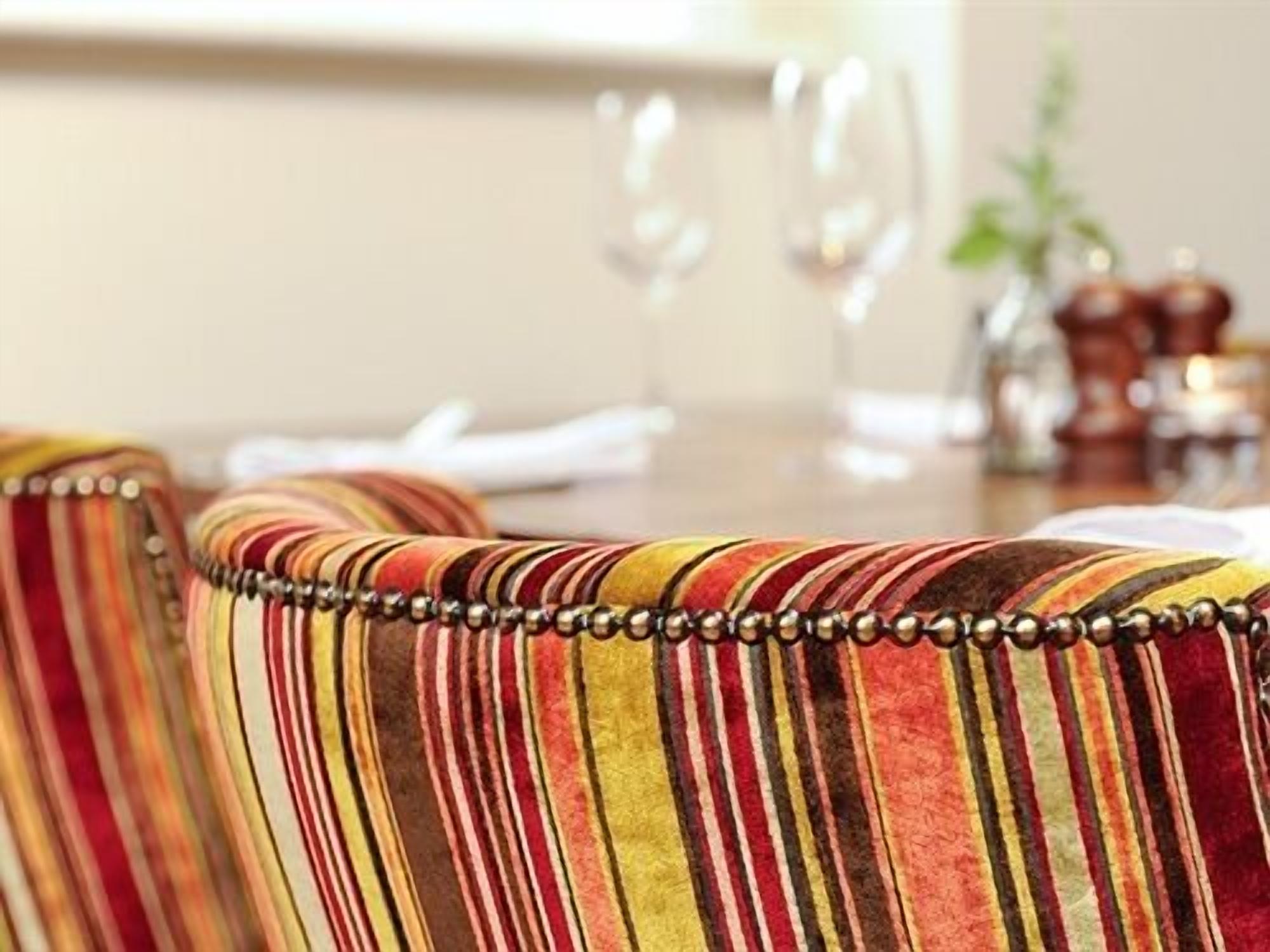 Un comedor con sillas tapizadas a rayas y una mesa de madera.