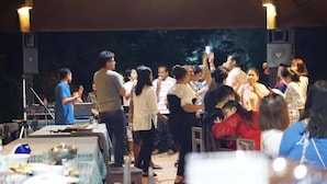 An outdoor event with people gathered around tables, some standing and others seated, under a covered area with tables set for dining. - Bangyai Buri Resort (Surat Thani)