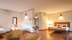 A hotel room with two single beds, a wicker chair, a small table with a vase, and a bicycle. - Bangyai Buri Resort (Surat Thani)