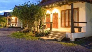 A row of single-story houses with a rustic design, featuring wooden doors and a gravel driveway. - Bangyai Buri Resort (Surat Thani)