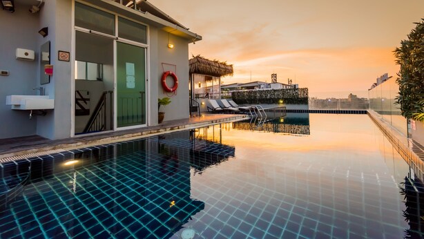 Ein modernes Hotel mit Schwimmbad, einer überdachten Liegefläche und Blick auf den Sonnenuntergang.