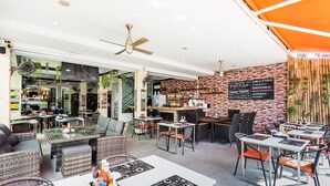 Ein modernes Restaurant mit Außenbereich, einer Speisekarte an der Ziegelwand und Deckenventilatoren.