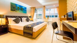 Ein Hotelzimmer mit einem großen Bett, einem Schreibtisch, einem Sessel und einem Fernseher.
