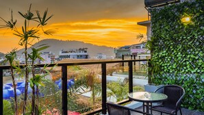 Ein Balkon mit Blick auf einen Sonnenuntergang, einem Glastisch und Stühlen.