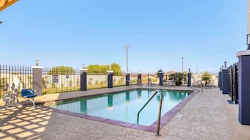 Una piscina al aire libre, sillones reclinables de piscina