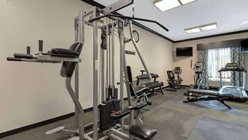 A gym with various exercise equipment, a treadmill, and a wall-mounted TV.