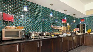 Un espace buffet agrémenté d’un mur à motifs, d’appareils électroménagers en acier inoxydable et de différents plats présentés.