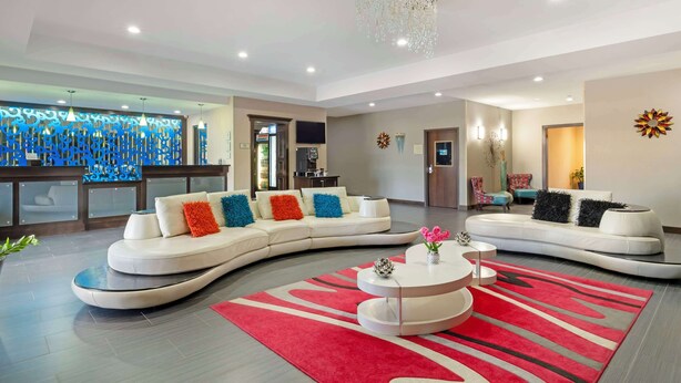 Un salon moderne avec un canapé blanc aux lignes courbes, un tapis rouge et gris, et une table basse blanche.