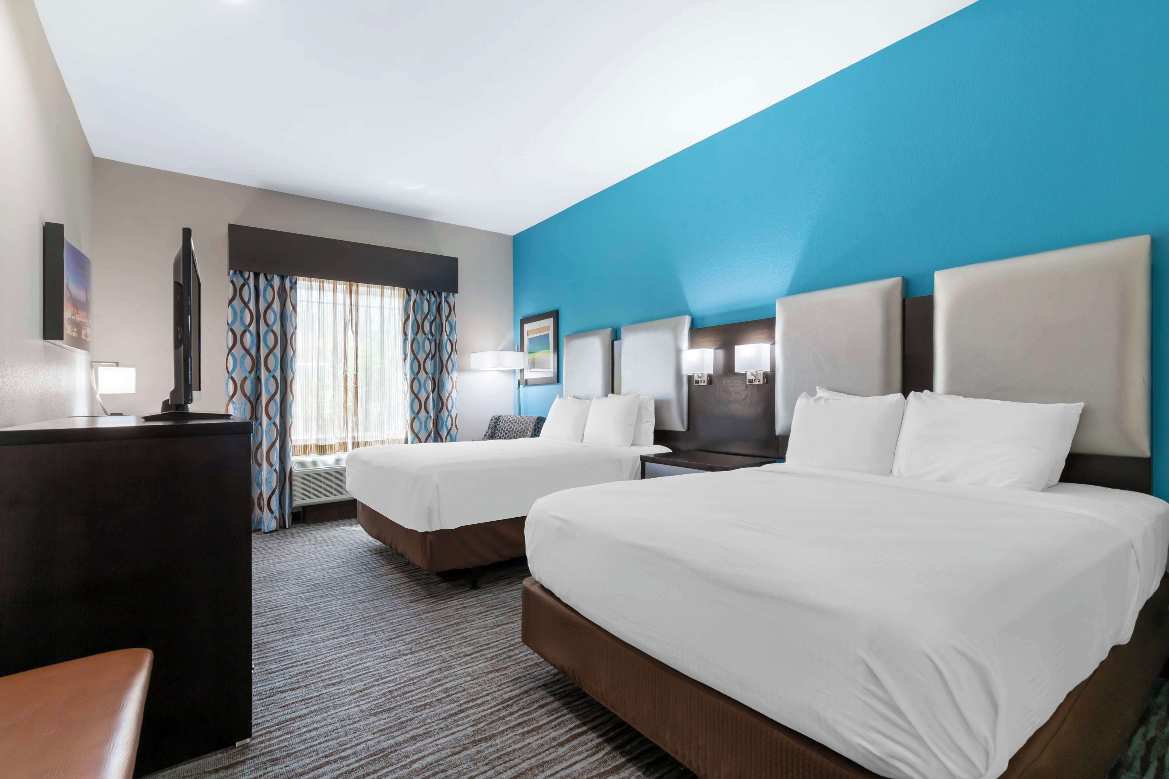 A hotel room with two beds, a desk, and a TV.