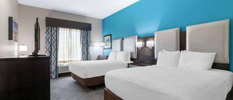 A hotel room with two beds, a desk, and a TV.