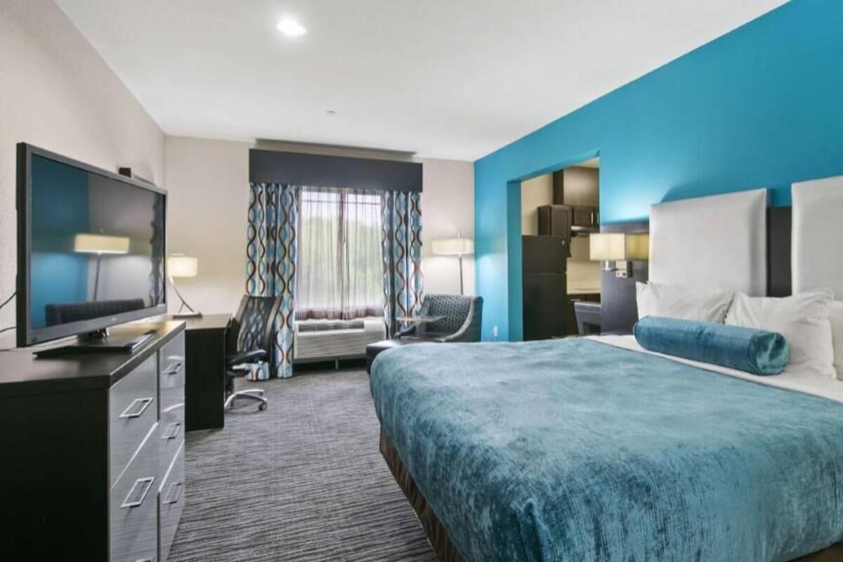 A hotel room with a large bed, a television, a desk, and a chair.