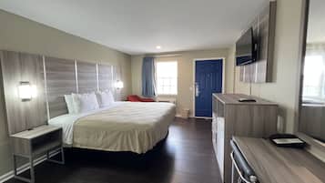 Een hotelkamer met een groot bed, nachtkastjes, een bureau, een stoel, een televisie en een deur.