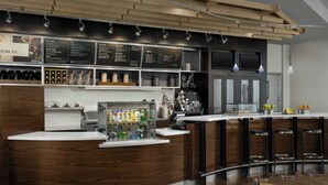 Zona de bar moderna con mostrador de madera, taburetes y un panel de menú.