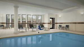 Una piscina interior con sillones de descanso y vistas al exterior.