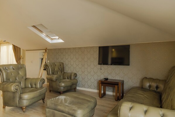 A living room with a sofa set, a television, and a ladder leaning against the wall.