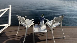 A wooden deck with two white chairs and a small table, overlooking a calm body of water with a clear sky above. - Lale Boutique Hotel (Sapanca)